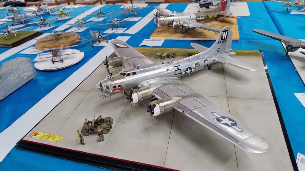 Fileiras de aviões em miniatura nas mesas do 2º Open de Sorocaba de plastimodelismo, destacando caças da Segunda Guerra Mundial com pintura detalhada.