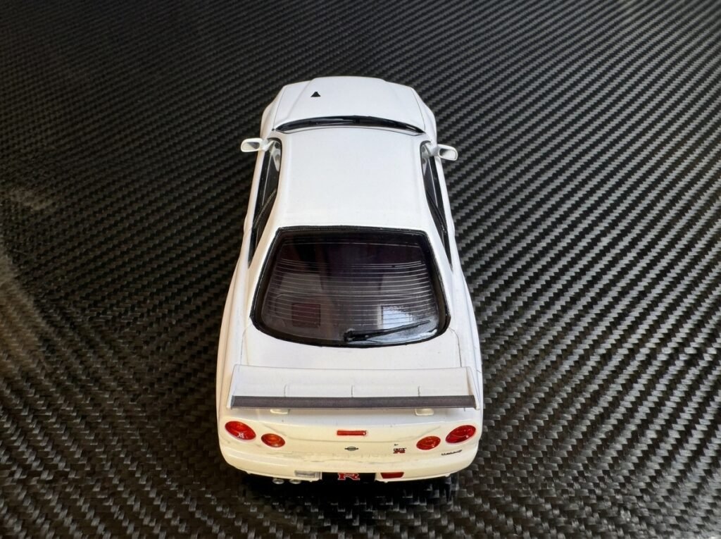 Modelo finalizado do Nissan Skyline GT-R Tamiya 1/24 V-Spec II em ângulo diagonal exibindo o brilho da carroceria.