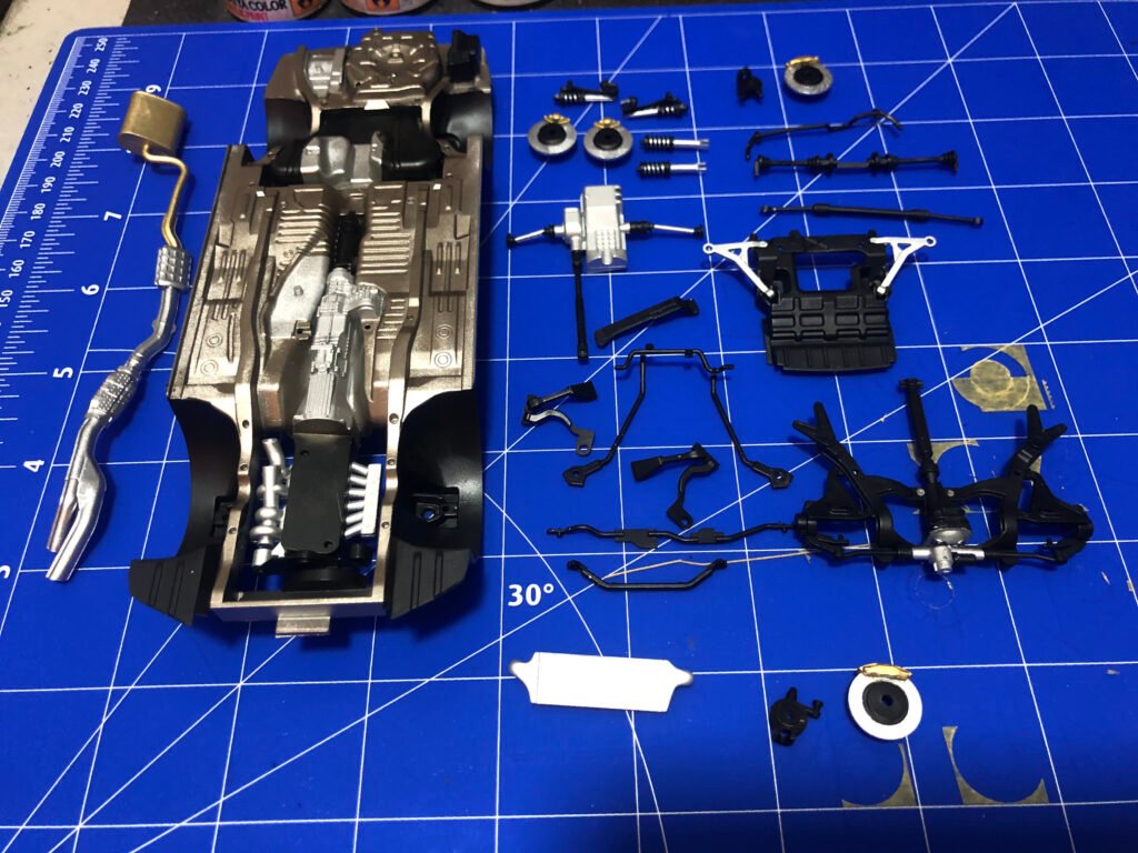 Visão inferior do chassi montado do Nissan Skyline GT-R Tamiya 1/24 com sistema de escapamento e transmissão detalhados. peças prontas