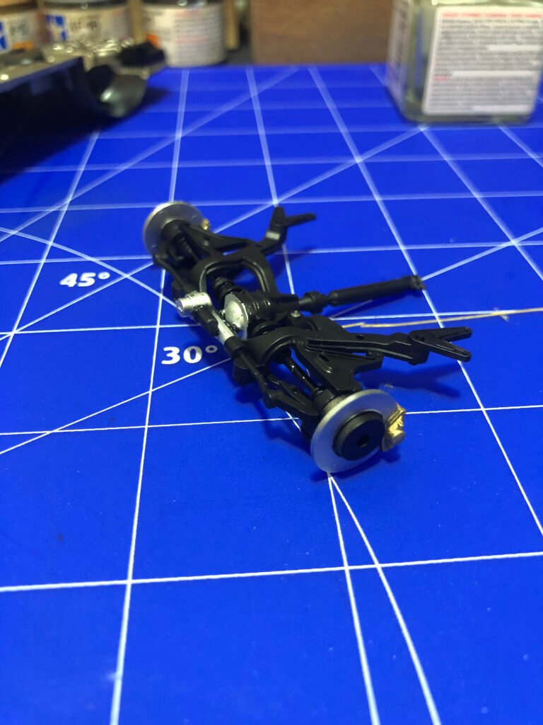 Detalhe técnico da suspensão montada do kit Nissan Skyline GT-R Tamiya 1/24 destacando amortecedores e molas pintados.
