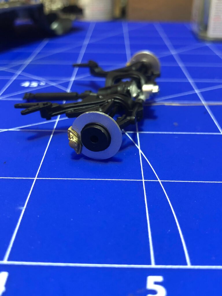 Detalhe 3 técnico da suspensão montada do kit Nissan Skyline GT-R Tamiya 1/24 destacando amortecedores e molas pintados.