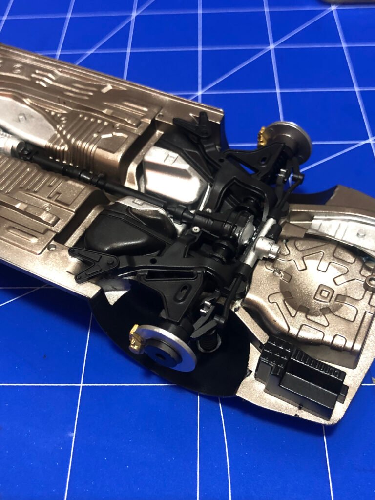 Detalhe 2 técnico da suspensão montada do kit Nissan Skyline GT-R Tamiya 1/24 destacando amortecedores e molas pintados.