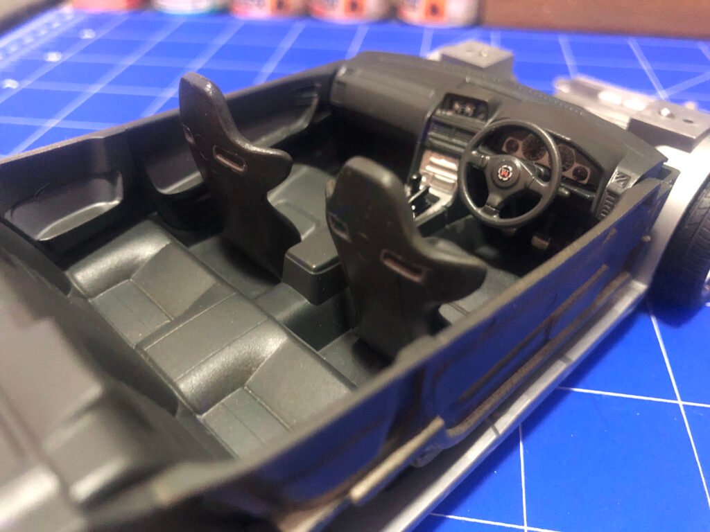 Interior do carro em miniatura do Nissan Skyline GT-R Tamiya 1/24 mostrando painel com decalques e bancos esportivos.